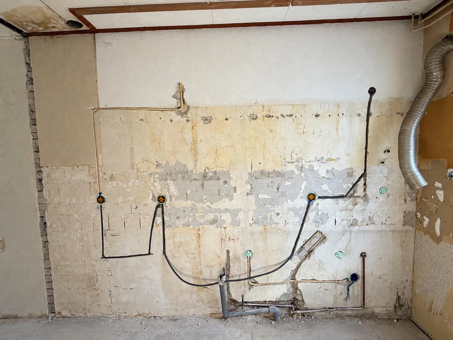 Nieuwe elektraleidingen en inbouwdozen in een gestripte keukenwand