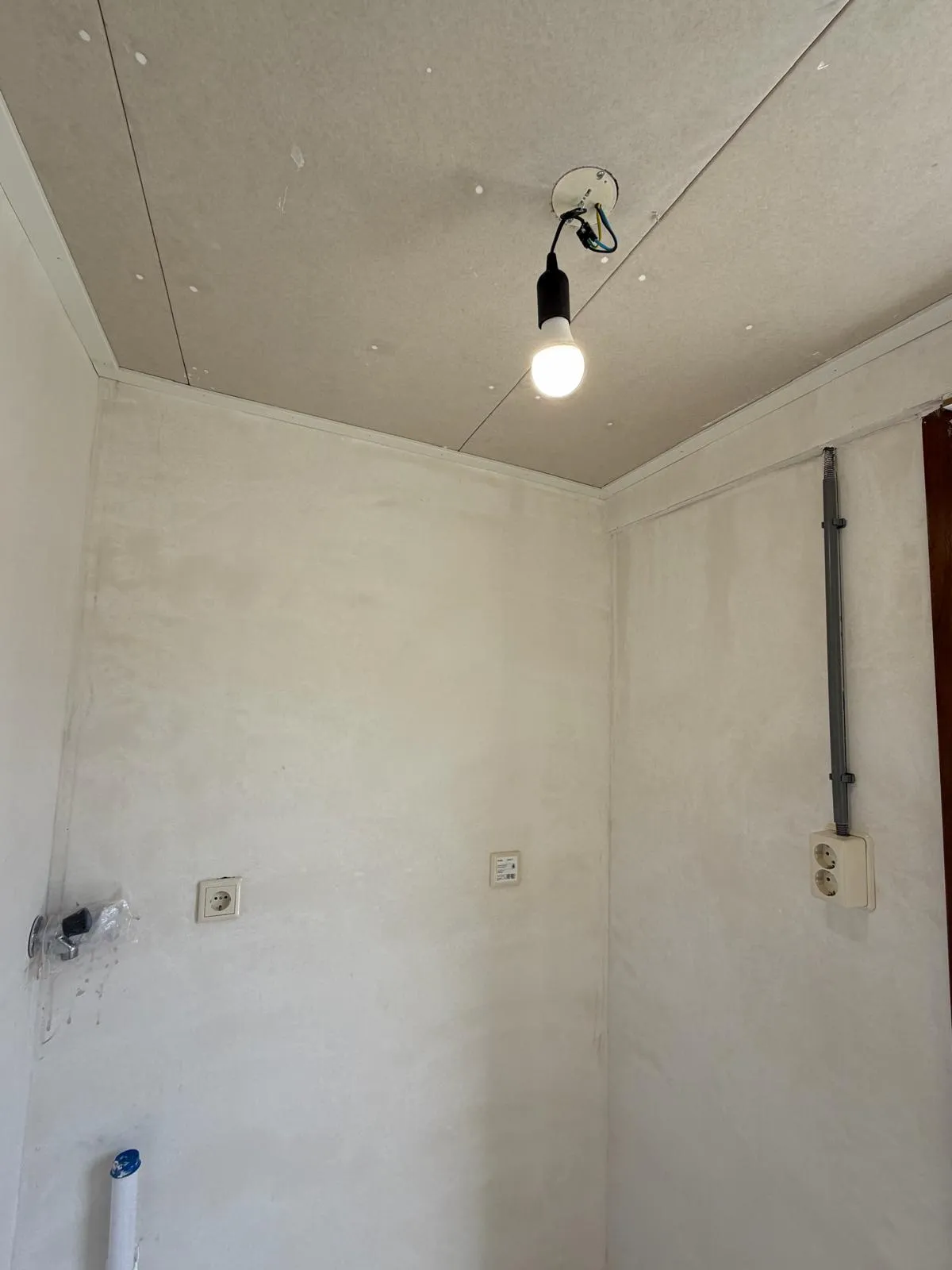 Nieuw aangelegd lichtpunt en stopcontacten in een kamer tijdens een renovatie